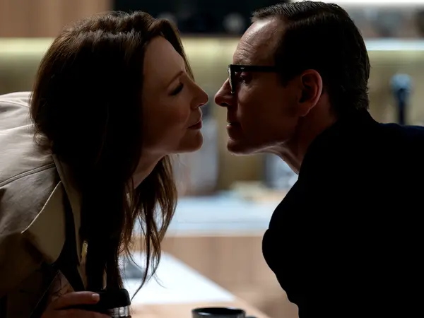 Man and woman with dark hair facing each other closely in intimate pose, soft lighting, blurred background.