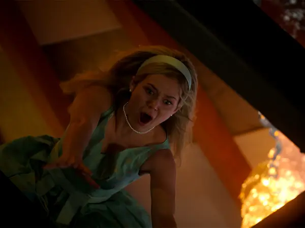 A woman with blonde hair in a green dress appears shocked, with a surprised expression on her face.