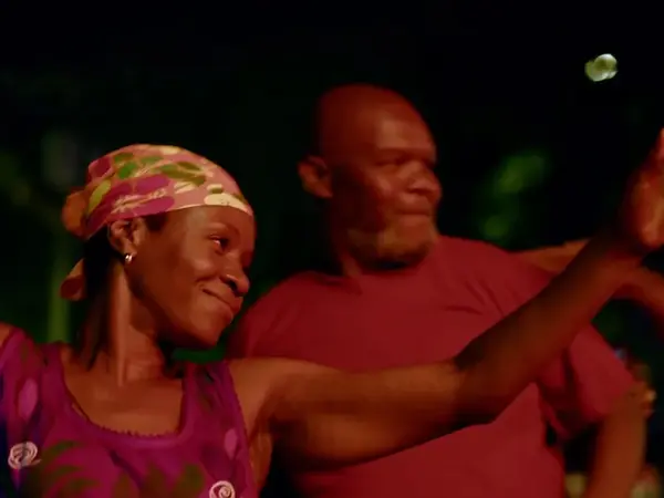 Two people in colourful clothing embracing outdoors at night.