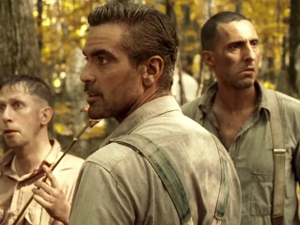 Three men in military uniforms in a forest setting.