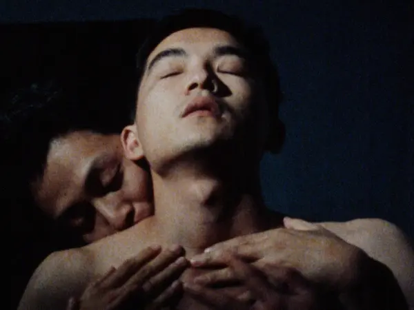 A close-up image of two shirtless Taiwanese men standing together in an embrace.