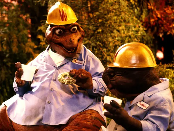 Two construction workers, one wearing a yellow hardhat, chatting on a worksite.